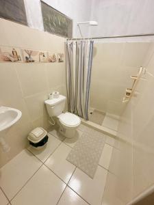 a white bathroom with a toilet and a shower at Otorongo Guest House in Iquitos