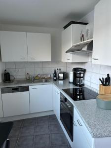 a kitchen with white cabinets and black appliances at Kassel Apartment am Entenanger in Kassel