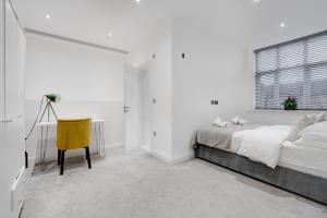 a white bedroom with a bed and a yellow chair at The calm apartment with 2 ensuite bedrooms. in Preston