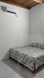 a bed in a white room with a floral bedspread at Lidxi Stagabeñe in Juchitán de Zaragoza