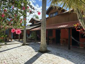 a building with palm trees in front of a brick courtyard at Chalés Solana localizados 50 metros do mar in Garopaba