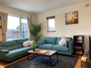 sala de estar con sofá azul y mesa en Yotei Chalets, en Niseko