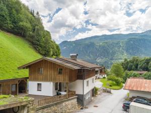 a house on a hill with mountains in the background at Apartment Leiter in Bramberg am Wildkogel