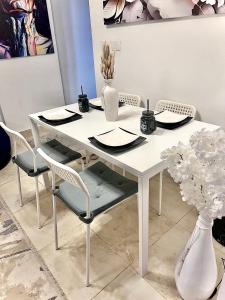 una mesa blanca con sillas y un jarrón con flores en Madinaty en Madinaty