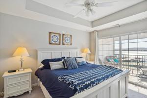 a bedroom with a bed with a blue comforter and a window at Condo with Balcony and Views in Lake of the Ozarks in Lake Ozark +16 photos