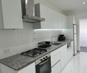 a white kitchen with a stove and a sink at Urbano Esquel in Esquel