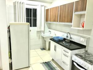 La cuisine blanche est équipée d'un évier et d'un réfrigérateur. dans l'établissement Apartamento Privado - 2 quartos, varanda, sala e cozinha integrada, à Piracicaba