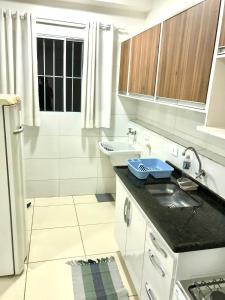 une petite cuisine blanche avec un évier et un évier dans l'établissement Apartamento Privado - 2 quartos, varanda, sala e cozinha integrada, à Piracicaba