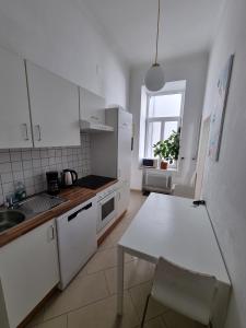 a kitchen with white cabinets and a table and a window at Apartment Dahlia Vienna in Vienna