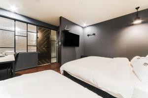 釜山にある2 Heaven Hotel Songdoのベッド2台とテレビが備わるホテルルームです。