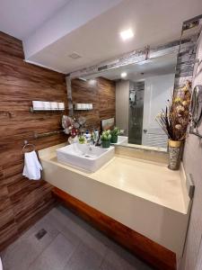 La salle de bains est pourvue d'un lavabo et d'un grand miroir. dans l'établissement KAMALA 503 ACACIA ESTATE TAGUIG CITY, à Manille