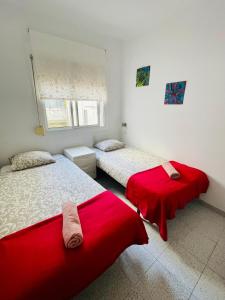 two beds in a room with red sheets at Barca 1 in Barcelona