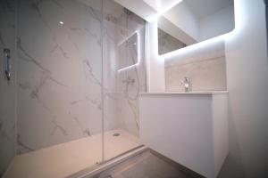 a white bathroom with a shower and a sink at Smart Appart - City Center Liege in Liège