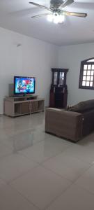 a living room with a couch and a flat screen tv at Casa Temporada em Aparecida com vista para Basílica in Aparecida