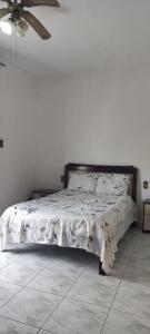 een bed in een slaapkamer met een witte muur bij Casa Temporada em Aparecida com vista para Basílica in Aparecida