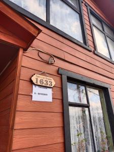 une maison en bois avec un panneau sur son côté dans l'établissement Hospedaje María Elena, à Coyhaique