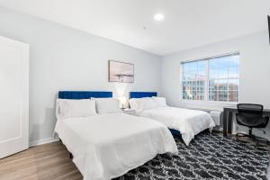 a white bedroom with two beds and a desk at Urban Elegance: 20 Minutes to NYC (Gym, Laundry) in Jersey City