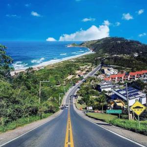 an empty road next to a beach with the ocean at Dunas Tiny House casa 1 in Florianópolis