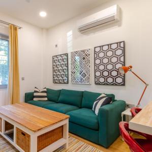 uma sala de estar com um sofá verde e uma mesa em Academia apartments by the park em Atenas