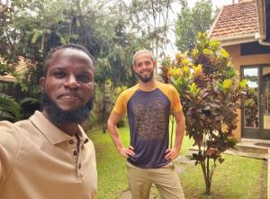 two men standing in front of a house at TGS Homestay in Kampala