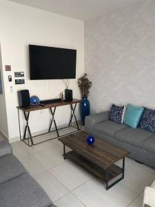 a living room with a couch and a table with a tv at Casa Completa con Alberca privada in La Paz