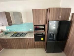 uma cozinha com armários de madeira e um frigorífico preto em Casa Completa con Alberca privada em La Paz