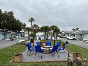 un patio con sillas azules, una mesa y un aparcamiento en Gulf Coast Inn, en Gulf Breeze