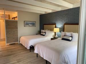 1 dormitorio con 2 camas y pared de ladrillo en Gulf Coast Inn, en Gulf Breeze