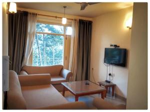 a living room with a couch and a table and a tv at Modern 2 bedroom apartment Near Nainital and Kaichi Dham SF4 in Nainital