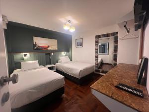 a hotel room with two beds and a desk at La Casa del Viajero in Lima