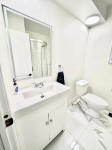 a white bathroom with a sink and a toilet at Main floor Room with Queen Bed, Free Parking and Free wi-fi and shared washroom near Fairview Park Mall (Room 2) in Kitchener