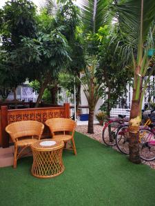 une terrasse avec 2 chaises, une table et des arbres dans l'établissement บุญเมืองน่าน, à Nan