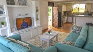 Casa Marabella A2 في شاطئ دياني: غرفة معيشة مع أريكة زرقاء وتلفزيون