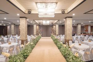 um salão de banquetes com mesas brancas e cadeiras brancas em Taman Prakerti Bhuana Hotel em Gianyar
