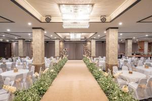 吉安雅Taman Prakerti Bhuana Hotel的摆着白色桌子和椅子的宴会厅