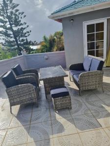 a patio with wicker furniture and a table and chairs at Green Door Oasis in Christ Church