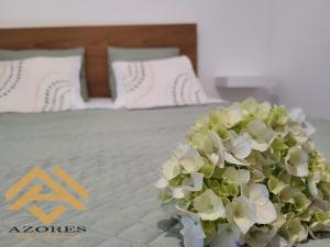 a bouquet of flowers sitting on top of a bed at Azores village apartments in Fontinhas