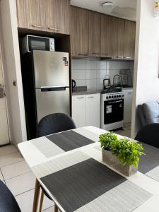 a kitchen with a table and a refrigerator at Depto cómodo ideal para familias, 3 habitaciones, wifi, estacionamiento privado, cercano a paramericana 5 in Rancagua