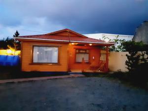 uma pequena casa laranja com um céu escuro em Cabañas OtilNau em Puerto Natales