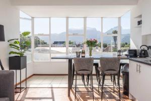 kuchnia ze stołem z krzesłami i dużym oknem w obiekcie Apartment with stunning views of Table Mountain w Kapsztadzie