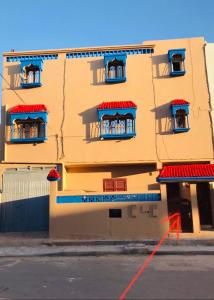un edificio con ventanas rojas y azules y una calle en Maison d’hôtes ATLAS ait alla, en Tan-Tan Plage