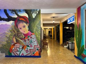 a painting of a woman holding a monkey in a hallway at Hotel Cosmos in Tamasopo