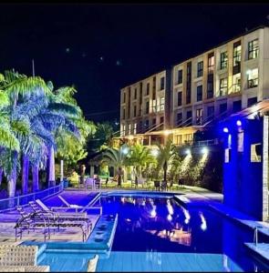 une piscine avec des chaises et des palmiers en face d'un bâtiment dans l'établissement Alto Da Serra Villas, à Bananeiras