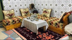 een vrouw op een bank met een tafel in een kamer bij Maison d’hôtes ATLAS ait alla in Tan-Tan Plage