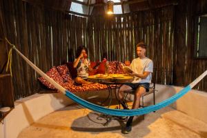 Ein Mann und eine Frau sitzen an einem Tisch in einer Hängematte in der Unterkunft Villa Maya - Glamping - Natural Reserve in Cozumel