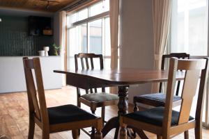 a dining room table with chairs and a kitchen at はなれ奏HanareSou-天然温泉付き貸別荘-1棟貸し in Kirishima