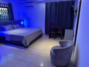 a bedroom with a bed and a chair and a table at D Barfi Guesthouse, excellent location in Kumasi