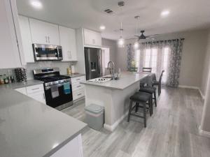 a kitchen with white cabinets and a kitchen island with chairs at Pool House Newly Remodeled 3bed 3bath Near DT Summerlin and Red Rock in Las Vegas