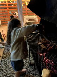 una joven está cocinando comida en una parrilla en Cabaña Cardinal, en Puerto Varas