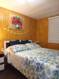 1 dormitorio con 1 cama y una pintura en la pared en Cabaña Cardinal, en Puerto Varas
